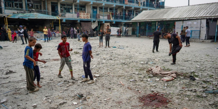 Palestinian boys stand near blood stains at a UN school housing displaced people that was hit during Israeli bombardment in Nuseirat in the central Gaza Strip. ©AFP