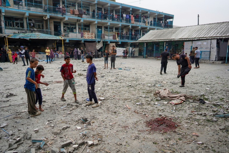 Palestinian boys stand near blood stains at a UN school housing displaced people that was hit during Israeli bombardment in Nuseirat in the central Gaza Strip. ©AFP