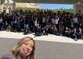 This handout picture released by Meloni's office shows Prime Minister Giorgia Meloni shooting a selfie with the press. ©AFP