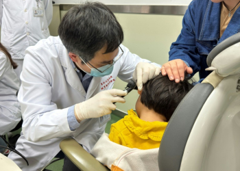 This handout picture courtesy of the Eye & Ent Hospital of Fudan University shows Dr Yilai Shu examining a young patient at the Eye & ENT Hospital of Fudan University in this image taken on April 17, 2024. ©AFP