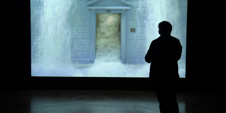 A journalist watches Bill Viola's video 'The Deluge' during a press preview of a 2017 exhibition at the Palazzo Strozzi in Florence. ©AFP