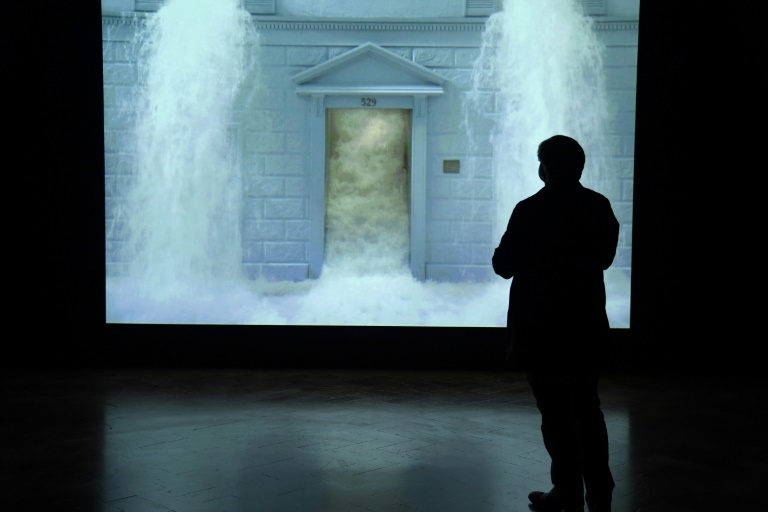 A journalist watches Bill Viola's video 'The Deluge' during a press preview of a 2017 exhibition at the Palazzo Strozzi in Florence. ©AFP