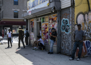 People stand outside a corner store during a summer heat wave in the Bronx borough of New York on July 11, 2024. ©AFP