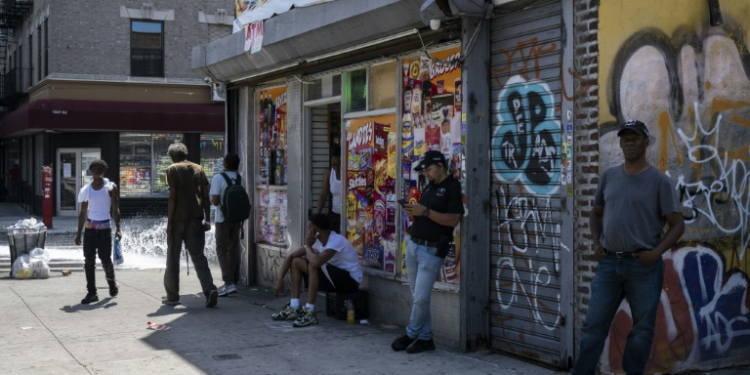 People stand outside a corner store during a summer heat wave in the Bronx borough of New York on July 11, 2024. ©AFP