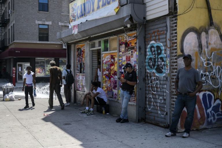 People stand outside a corner store during a summer heat wave in the Bronx borough of New York on July 11, 2024. ©AFP