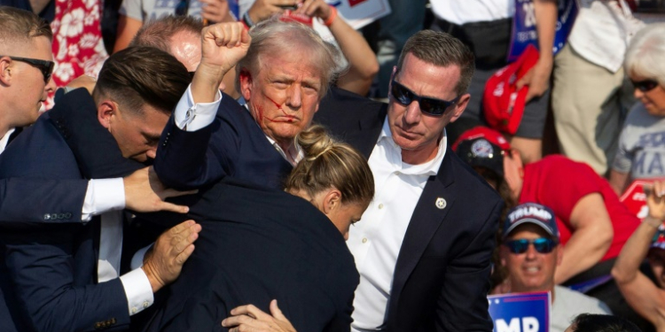 Republican candidate Donald Trump surrounded by Secret Service agents as he is taken off the stage. ©AFP