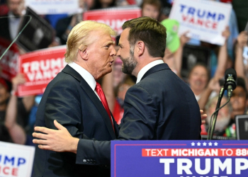 Republican nominee Donald Trump, wearing a new bandage on his ear after an attempted assassination, greets running mate J.D. Vance at a rally in Grand Rapids, Michigan / ©AFP