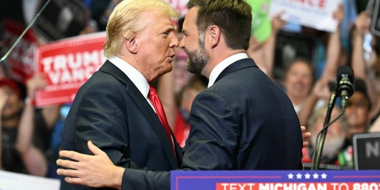 Republican nominee Donald Trump, wearing a new bandage on his ear after an attempted assassination, greets running mate J.D. Vance at a rally in Grand Rapids, Michigan / ©AFP