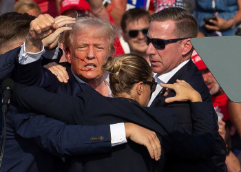 Donald Trump is seen with blood on his face surrounded by Secret Service agents as he is taken off the stage in Pennsylvania, on July 13, 2024 / ©AFP