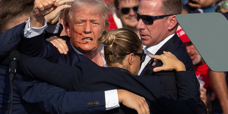 Donald Trump is seen with blood on his face surrounded by Secret Service agents as he is taken off the stage in Pennsylvania, on July 13, 2024 / ©AFP