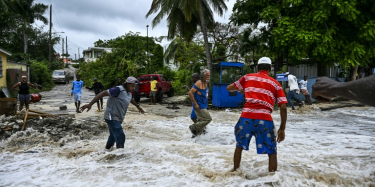 People walk through flooding from seawater after the passage of Hurricane Beryl in the parish of Saint James, Barbados. ©AFP