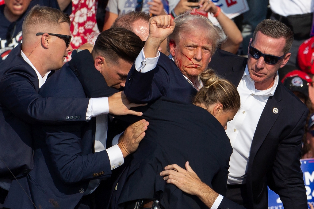 Donald Trump is seen with blood on his face surrounded by Secret Service agents as he is taken off the stage after an attempted assassination in Pennsylvania / ©AFP