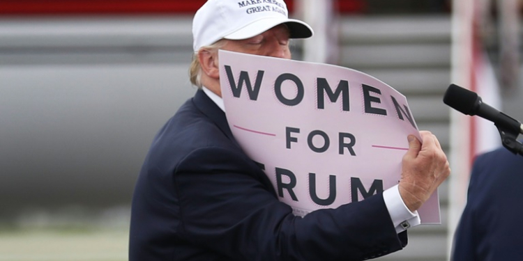 Donald Trump holds a sign that reads 'Women for Trump' during his 2016 presidential campaign, which was beset by scandal over his treatment of women. ©AFP