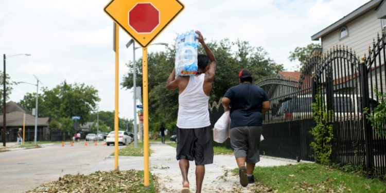 A man carries a container of water from a distribution center in Houston, Texas, on July 11, 2024. ©AFP