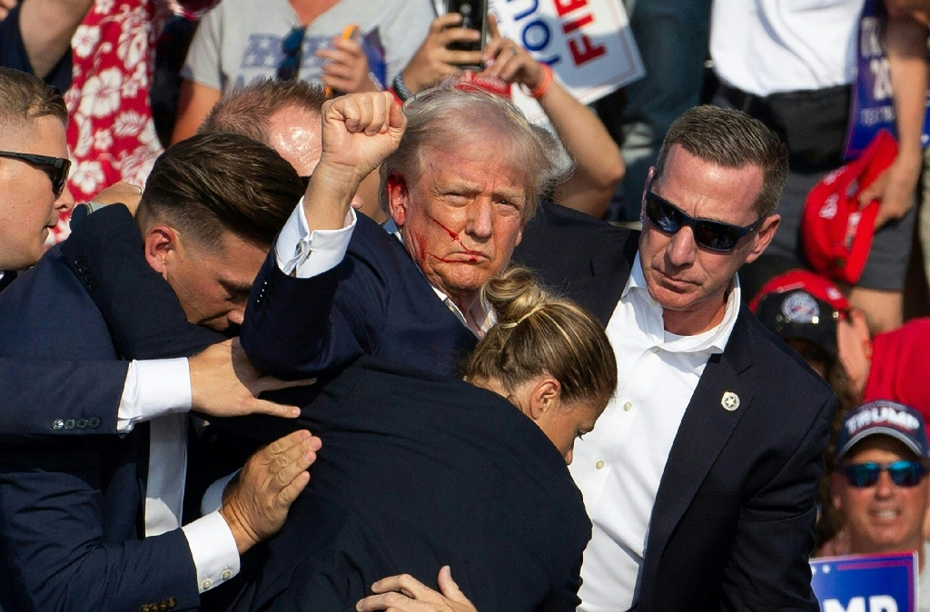 Republican candidate Donald Trump is seen with blood on his face surrounded by secret service agents as he is taken off the stage / ©AFP