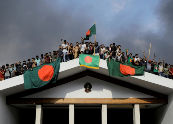 Anti-government protesters display Bangladesh's national flag as they storm Prime Minister Sheikh Hasina's palace in Dhaka. ©AFP