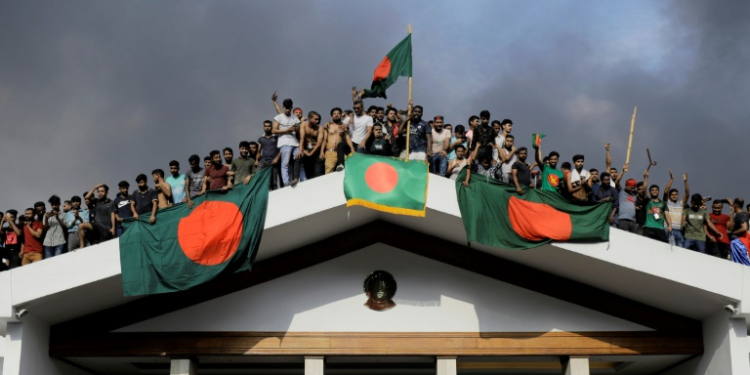 Anti-government protesters display Bangladesh's national flag as they storm Prime Minister Sheikh Hasina's palace in Dhaka. ©AFP