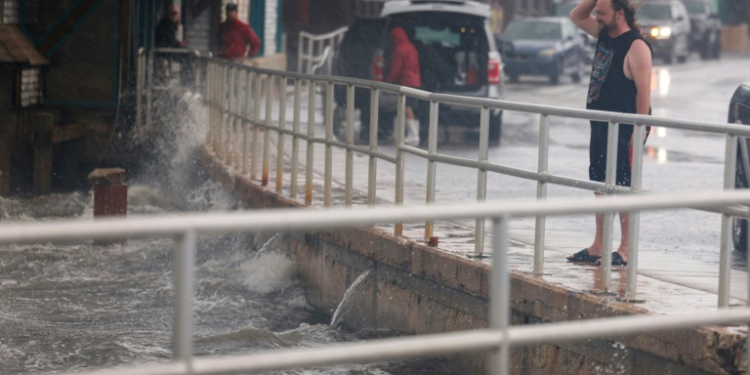 A rain-soaked man in Cedar Key, Florida observes waves kicked up by the winds of Tropical Storm Debby, which is strengthening as it moves through the Gulf of Mexico on August 04, 2024 . ©AFP