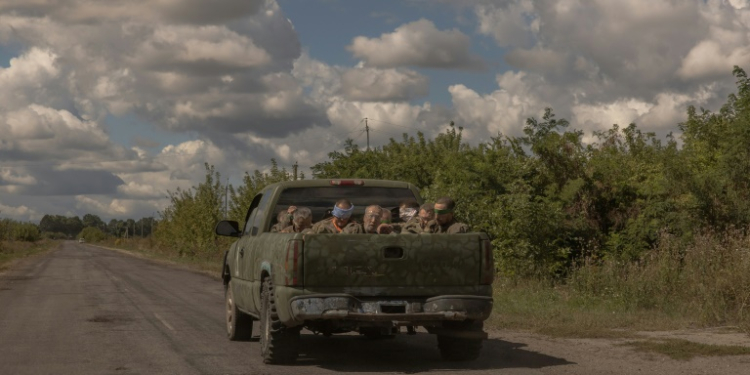 Around 10 blindfolded and bound men in Russian military fatigues being driven in a military vehicle away from the border crossing in the direction of the city of Sumy. ©AFP