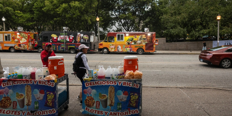 Migrants from Ecuador sell goods in Chicago -- migrants often have to wait months before they can apply for a work permit, and their cases are taking longer and longer due to excessive demand on the immigration court system / ©AFP