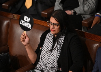 In the cartoon, a woman identified as Rep. Tlaib is seen sitting at a desk next to an exploding electronic device / ©AFP