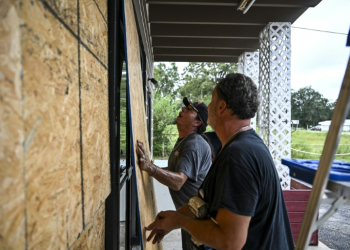 Rick Chouinard (R) and Donald Tointigh install boards over windows of their shop ahead of the arrival of Hurricane Helene in Crawfordville, Florida on September 25, 2024. ©AFP