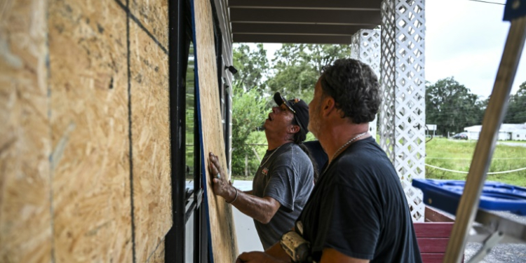 Rick Chouinard (R) and Donald Tointigh install boards over windows of their shop ahead of the arrival of Hurricane Helene in Crawfordville, Florida on September 25, 2024. ©AFP