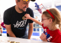 Nick Vucic gets an 'I Voted' sticker from his daughter Abigail, 7, after he casts his early vote at a polling station in Arlington, Virginia / ©AFP