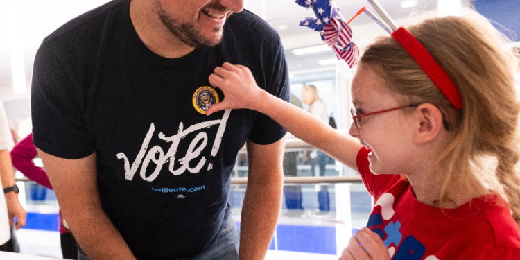 Nick Vucic gets an 'I Voted' sticker from his daughter Abigail, 7, after he casts his early vote at a polling station in Arlington, Virginia / ©AFP