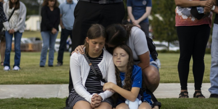 A mother and her children bow their heads in prayer at a vigil for the victims of the Apalachee High School shooting in Winder, Georgia. ©AFP