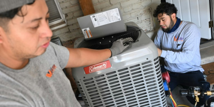 Technicians install a heat pump that replaces the furnace and air conditioner at Su Balasubramanian's home in Washington, DC. ©AFP