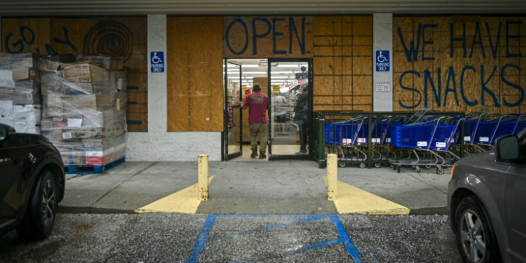 A person walks into a store boarded up with wood as preparations are made for the arrival of Hurricane Helene, in Steinhatchee, Florida, on September 25, 2024. ©AFP