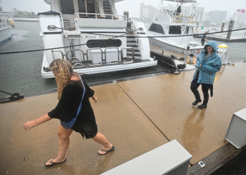 People walk along the marina of Sarasota, Florida as powerful Hurricane Milton nears the coast / ©AFP