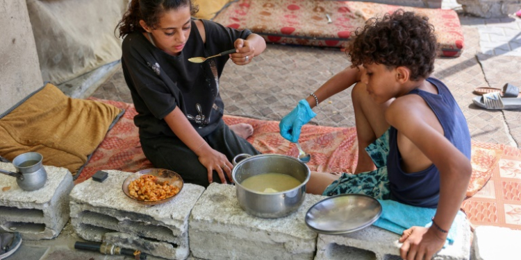 Displaced children eat a cooked meal in their tent at Gaza City's damaged Yarmouk stadium on October 14, 2024. ©AFP