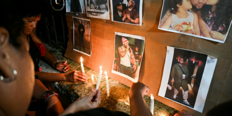 Cuban fans light candles next to pictures of the late singer, Jose Manuel Carbajal Zaldivar, known as 'El Taiger,' as they pay tribute in Havana. ©AFP