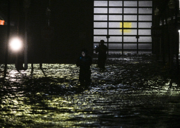 People take photos and videos as they walk through streets inundated by floodwaters after Hurricane Milton made landfall in Fort Myers / ©AFP