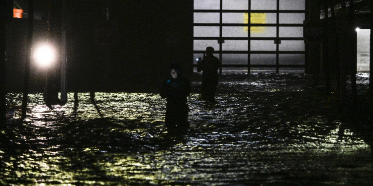 People take photos and videos as they walk through streets inundated by floodwaters after Hurricane Milton made landfall in Fort Myers / ©AFP