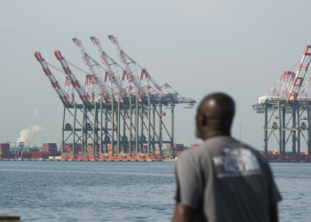 A man walks along a pier in Bayonne as cranes are visible at Port Newark in New Jersey, on October 4, 2024, where a port strike ended. ©AFP