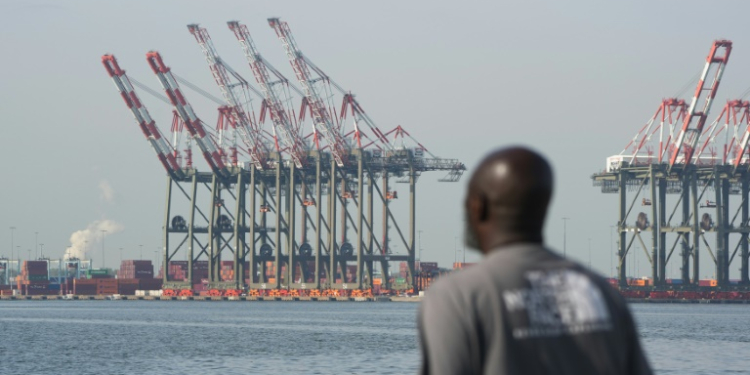 A man walks along a pier in Bayonne as cranes are visible at Port Newark in New Jersey, on October 4, 2024, where a port strike ended. ©AFP