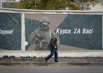 A man walks past a wall adorned with banners honouring Russian servicemen participating in Russia's military action in Ukraine. ©AFP