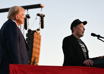 Elon Musk speaks on stage as he joins Donald Trump during a campaign rally / ©AFP