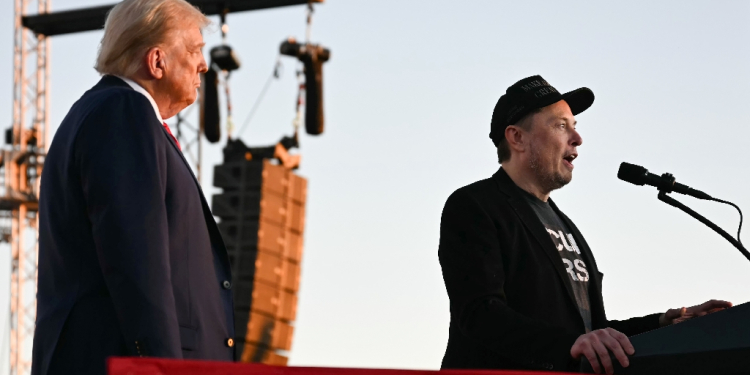 Elon Musk speaks on stage as he joins Donald Trump during a campaign rally / ©AFP