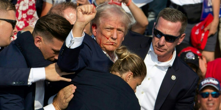 Republican presidential candidate Donald Trump ducked down as Secret Service agents flooded the stage during an assassination attempt in July. ©AFP