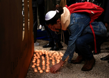 A mourner in Nice, France, lays down a candle at a ceremony in tribute of the victims of October 7 attack. ©AFP