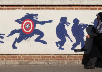 An Iranian woman walks past a mural on the side wall of the former US embassy in Tehran, the day after the presidential election won by Donald Trump / ©AFP