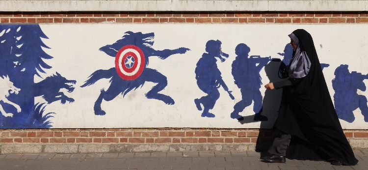 An Iranian woman walks past a mural on the side wall of the former US embassy in Tehran, the day after the presidential election won by Donald Trump / ©AFP