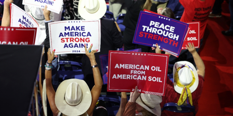 People hold signs that read American Oil from American Soil at a Trump rally  / ©AFP