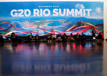 People sit and work next to a giant banner of the G20 Summit in Rio de Janeiro, Brazil, on November 18, 2024. ©AFP