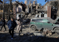 Local residents and police walk next to damaged cars and a destroyed building following a missile attack in Odesa. ©AFP