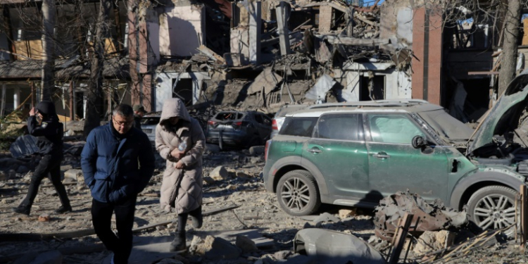 Local residents and police walk next to damaged cars and a destroyed building following a missile attack in Odesa. ©AFP